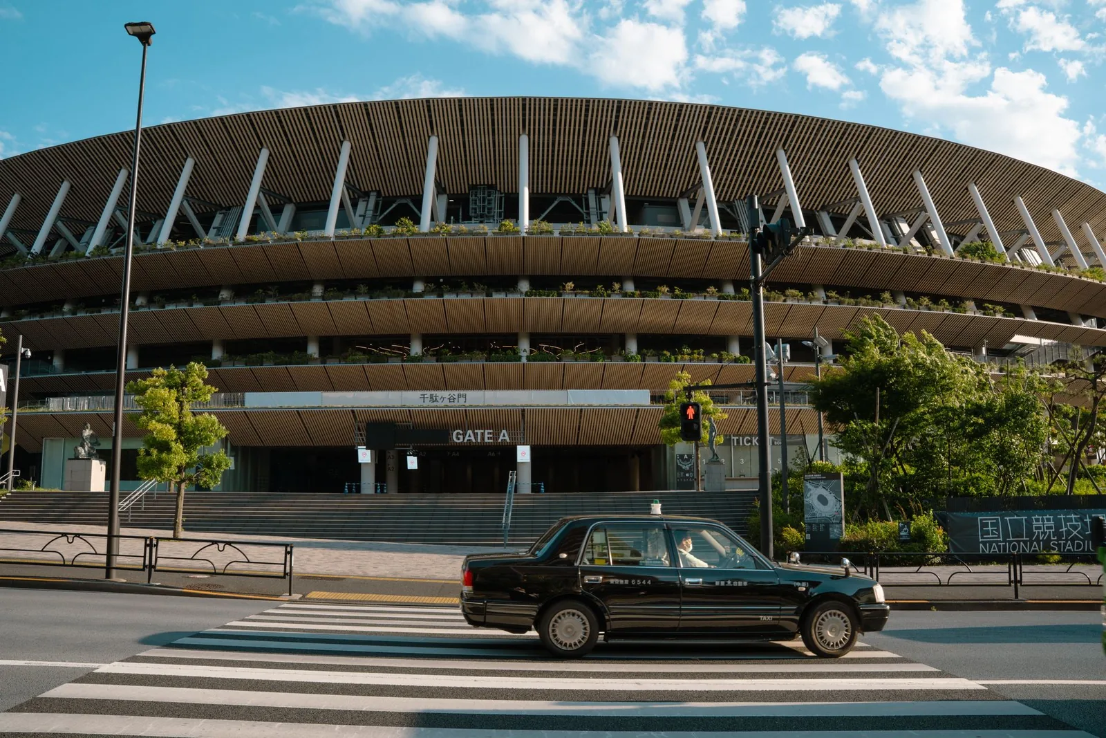 Tokion kansallisstadionin julkisivu ja ohi ajava taksi